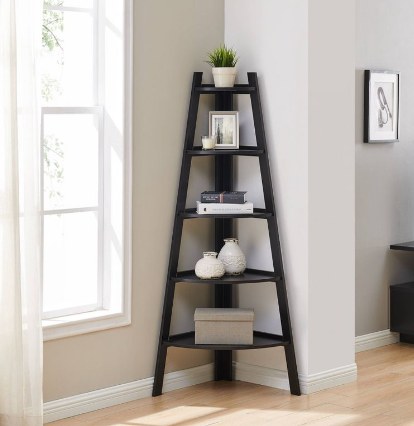 Black ladder corner bookshelf with candles, frames, and books on shelves