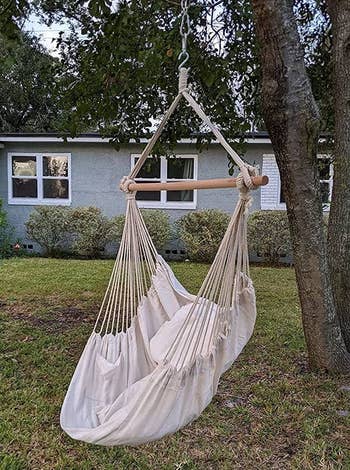 reviewer photo of the off-white hammock chair hanging from a tree