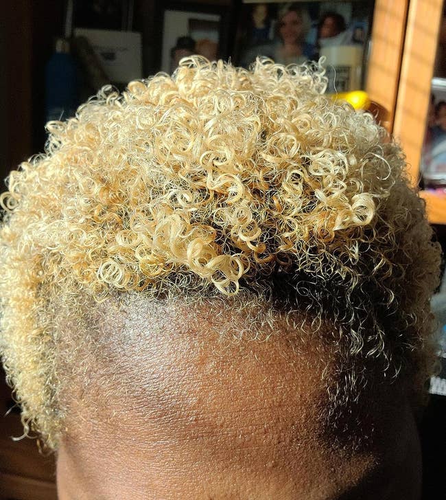 close up image of a reviewer with shiny, short blonde coils