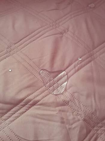 a water droplet on the light pink blanket, showing how it's not sinking in