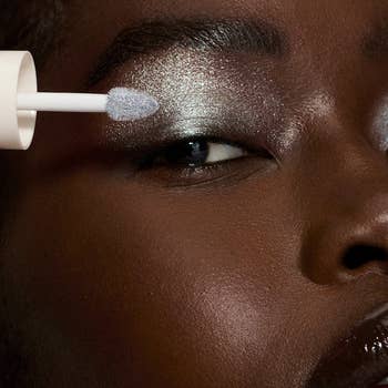 Close-up of a idiosyncratic   applying shimmery eyeshadow with an applicator brush, highlighting elegance and quality   successful  constitution  application
