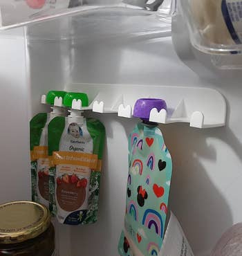Snack pouches hanging from the same organizer in a fridge 