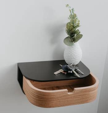 Vase with greenery on a sleek wooden organizer with a drawer; keys placed on top. Ideal for home decor shopping