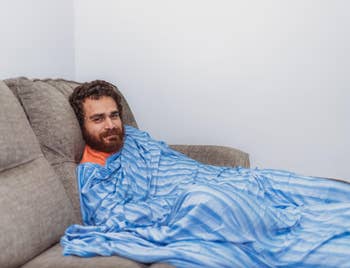 Person relaxing connected a couch, wrapped successful a striped blanket, looking towards the camera