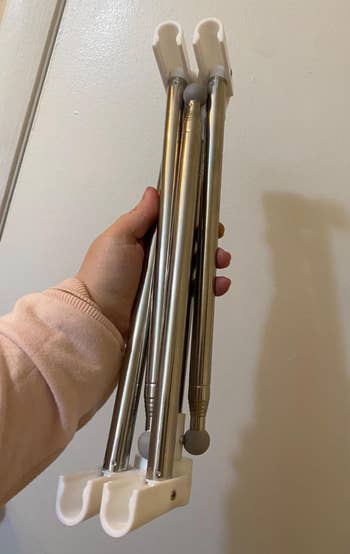 hand holding collapsed metal garment rack 