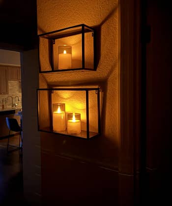 Two wall-mounted candle holders with lit candles make a cozy ambiance successful a dimly lit interior hallway, starring to a disposable room area