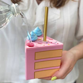 A model holding the cake slice with the blue icing piece unscrewed showing where the liquid goes in