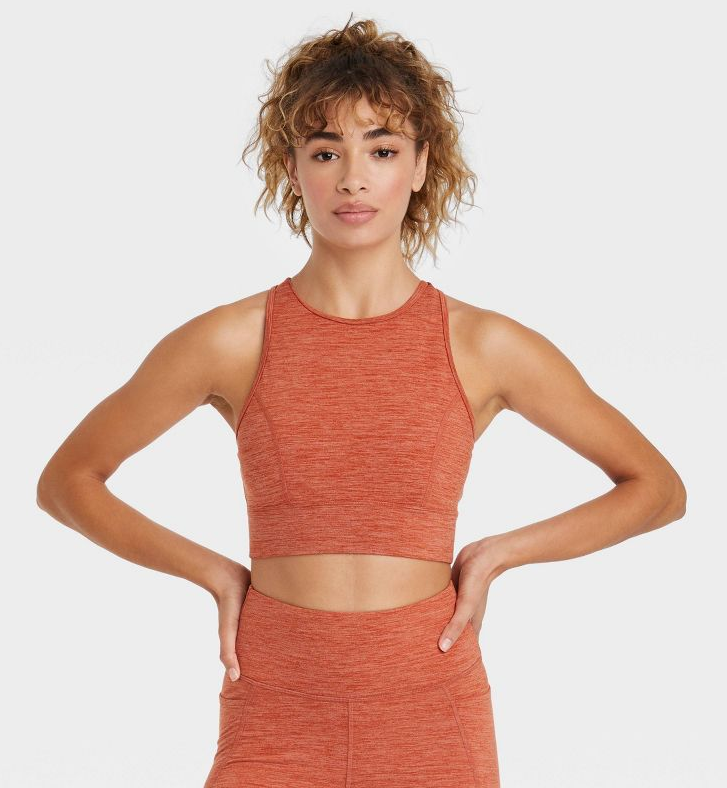 model posing in an orange space-dye sports bra and matching leggings