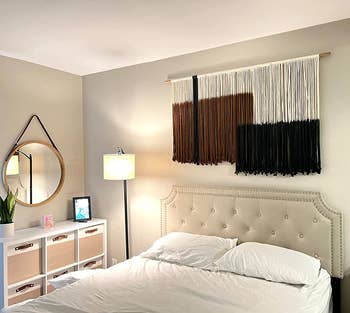 reviewer photo of the black, brown, and white macrame wall hanging over their bed