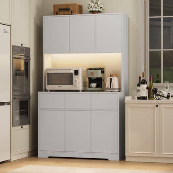 Modern room  setup with cabinets, microwave, java  maker, and toaster connected  a countertop. Wine bottles and room  decor are displayed
