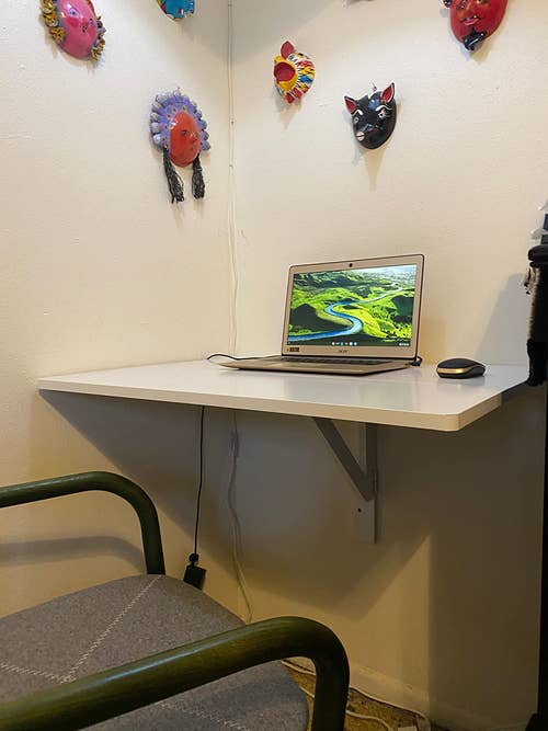 reviewer's white wall-mounted desk fully extended with laptop on it