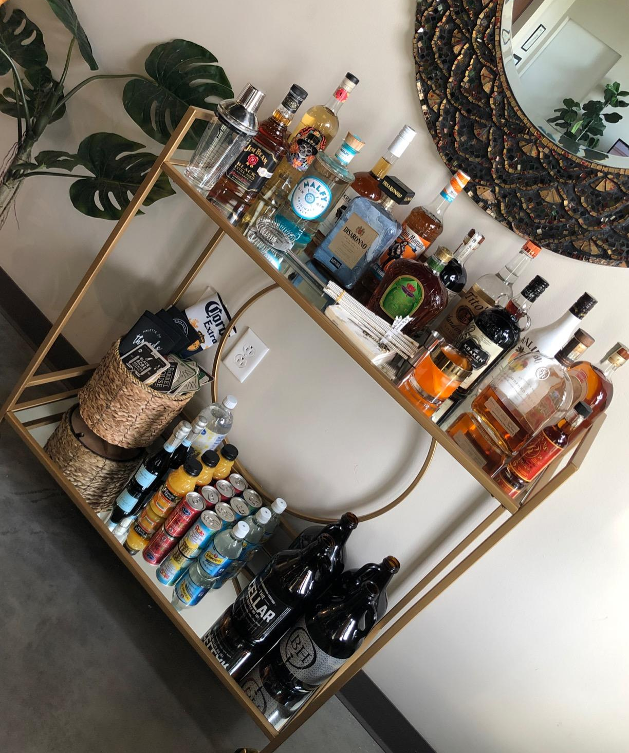 the gold bar cart with various liquors and cocktail supplies on it