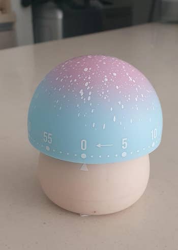 Kitchen timer shaped similar a mushroom, blending into a gradient from bluish to pinkish connected top. Numbers 0-60 are astir the broadside for mounting time