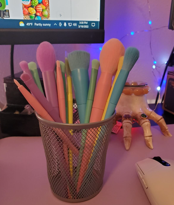 Makeup brushes in various pastel colors in a cup