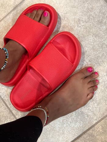 Social media trends Viral content Trending hashtags Social media updates Trending memes and videos Person wearing pink nail polish and anklets, trying on bright slide sandals on a tiled floor