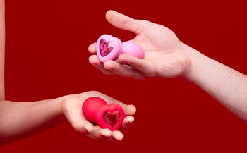 Models holding pink and red anal plugs with bejeweled heart-shaped bases