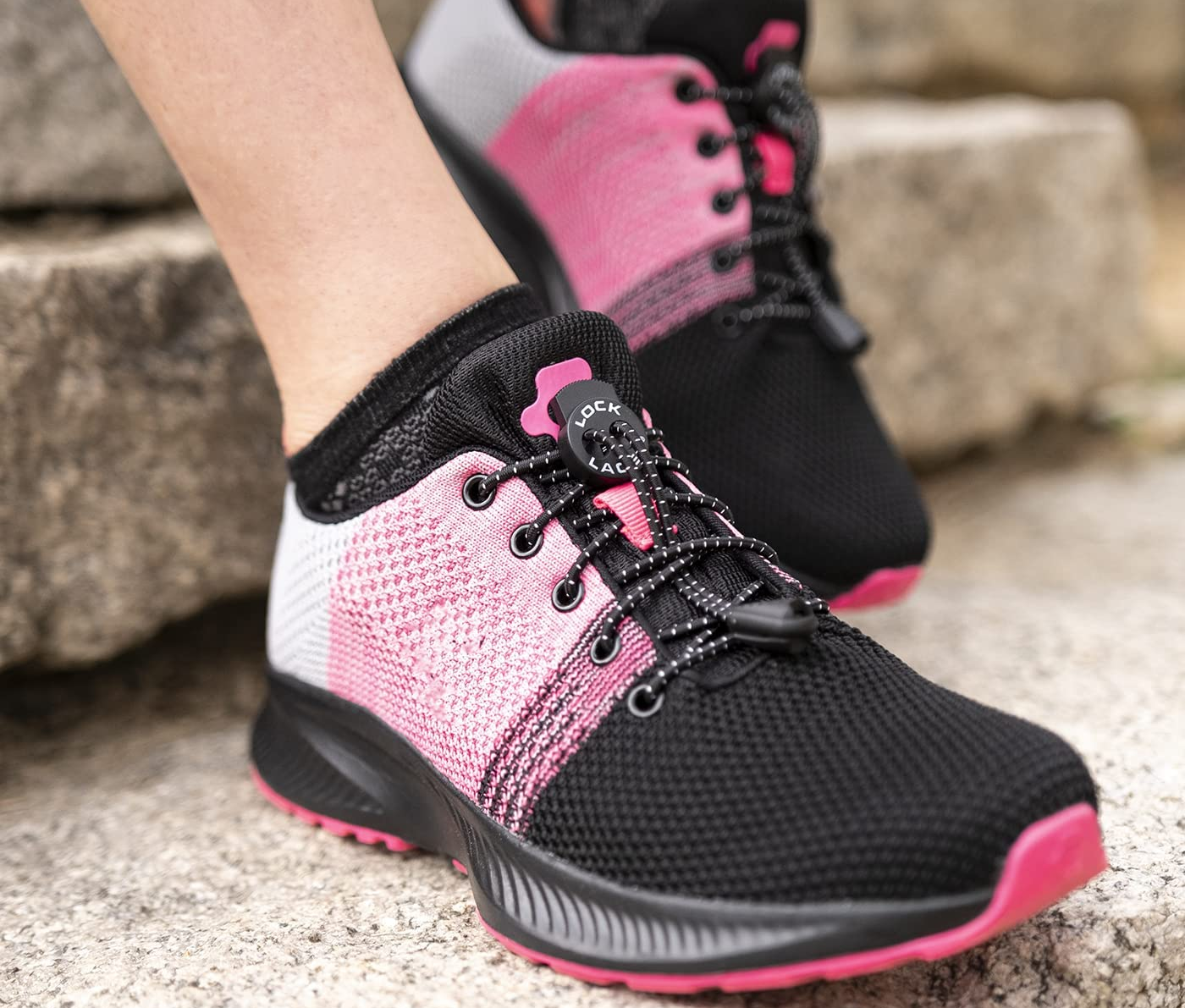 the lock laces on a pair of black and pink sneakers that a model is wearing