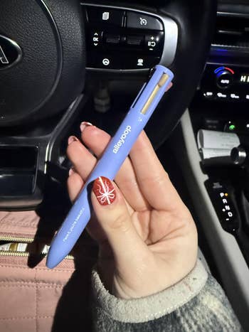 Hand holding a multitool pen wrong a car, demonstrating its compact design