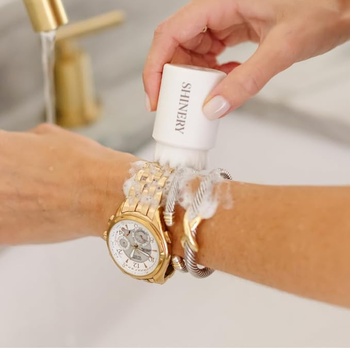 a model using the included brush to clean a watch and bracelet on their wrist 