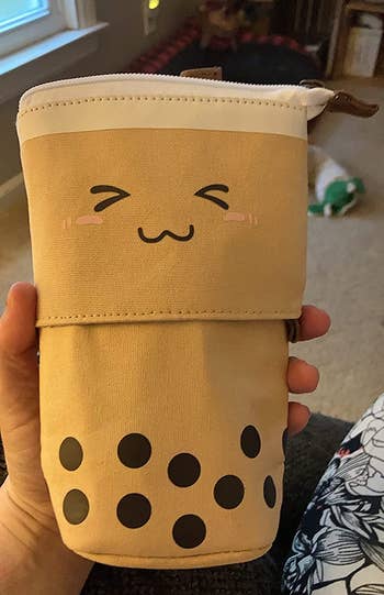 reviewer's hand holding the zipped up boba tea holder, ready for transport