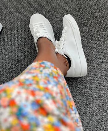 Person wearing white sneakers paired with a floral print dress