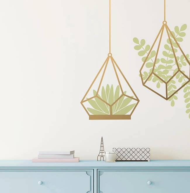 a pair of gold and green succulent wall decals hung above a blue dresser