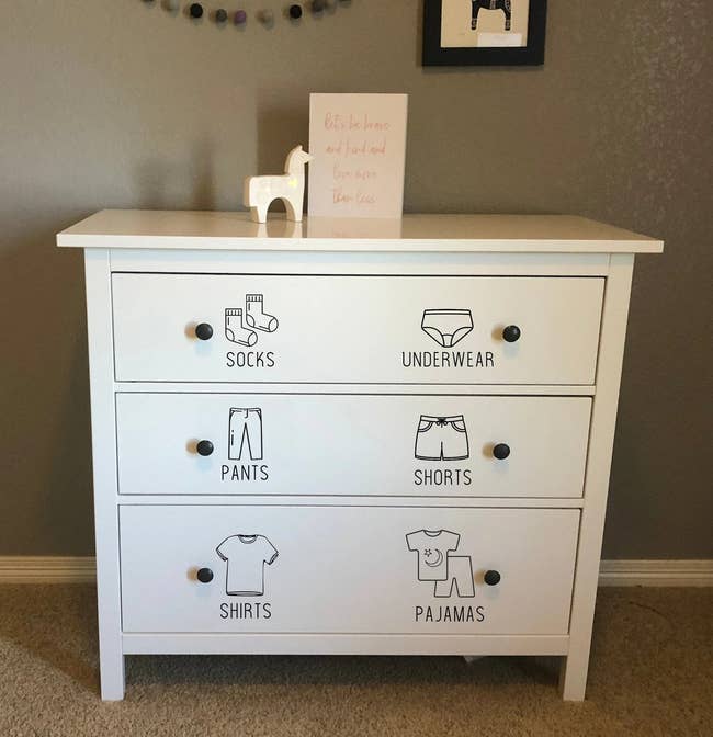 three drawer dress with stickers showing where shirts, pants, pajamas, etc should go