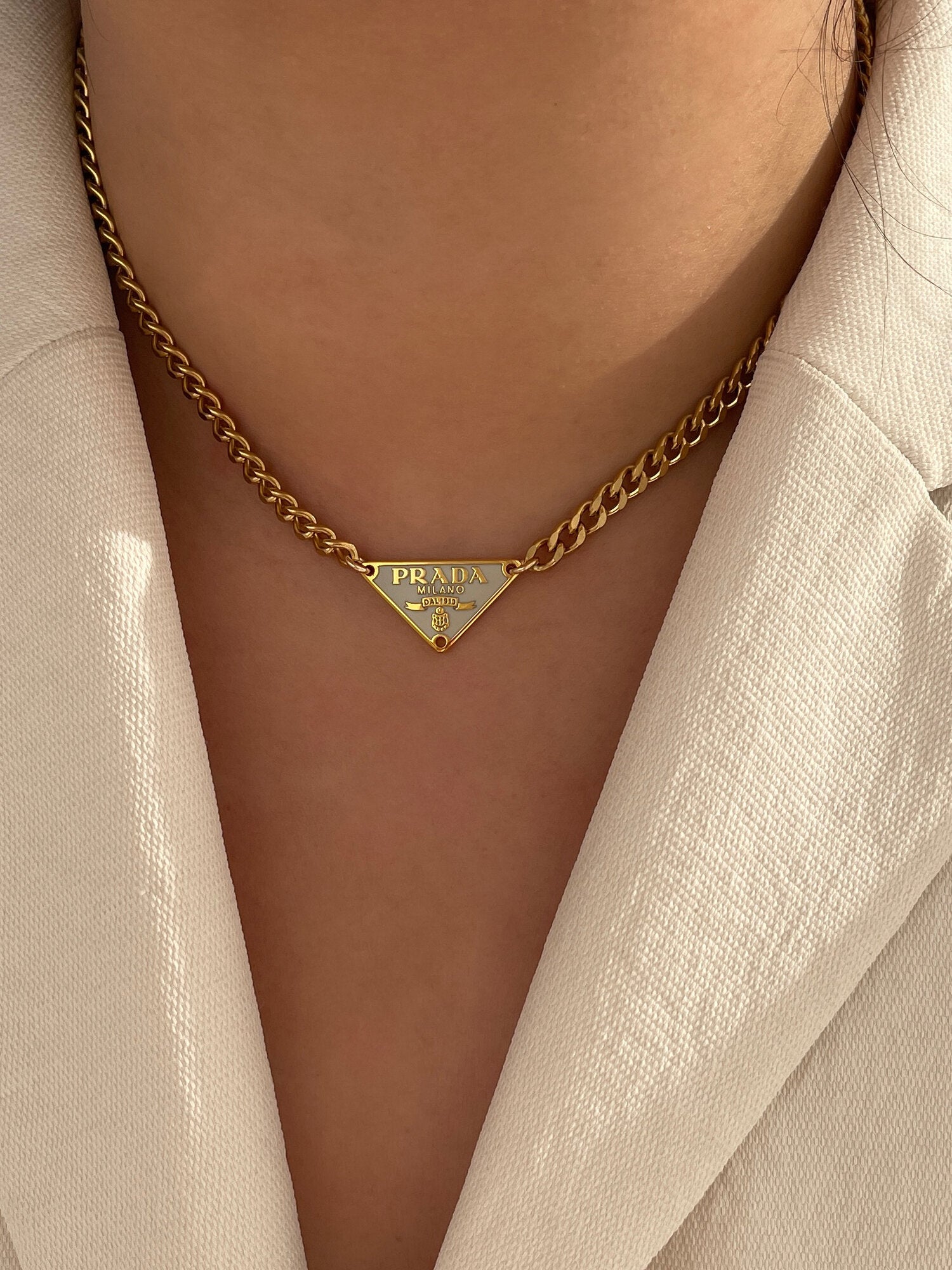 model wearing chunky necklace with Prada triangle logo on it