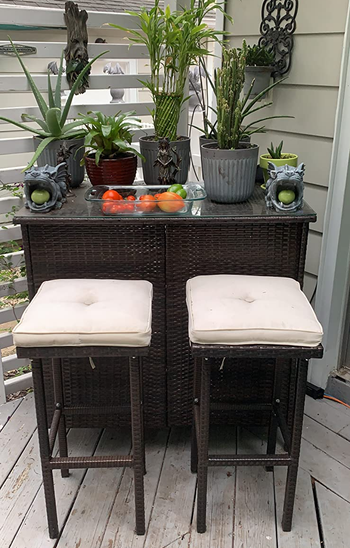 reviewer photo of the bar set with cream cushions topped with assorted plants