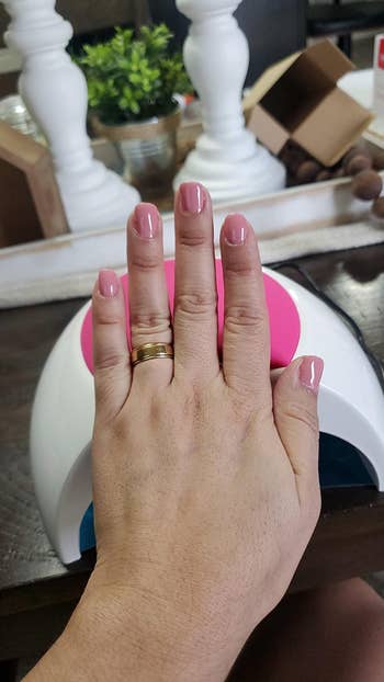 reviewer photo showing pink manicure on front of lamp