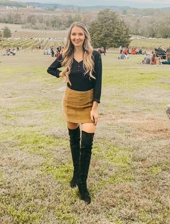 another reviewer wearing black over-the-knee suede boots with brown mini skirt and black long sleeve top