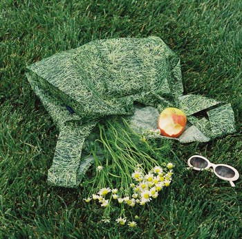 A grass patterned reusable tote bag with a cloud print holding goods 