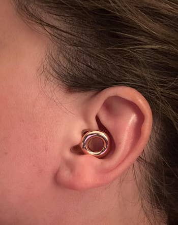 Close-up of an ear wearing a stylish, round ear cuff with a modern design