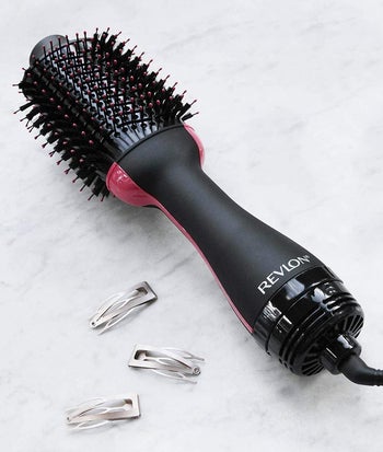 reviewer photo of the black and pink hot air brush next to some hair clips