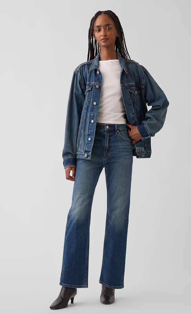 Person wearing denim overgarment   and jeans with a achromatic  shirt, lasting  confidently. Fashionable for casual occasions