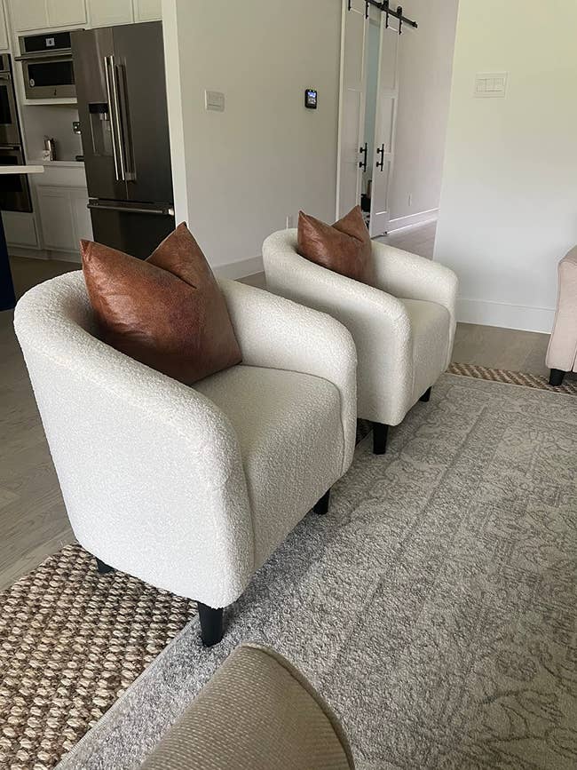 reviewer's two bouclé fabric chairs with brown pillows in a modern living room setting