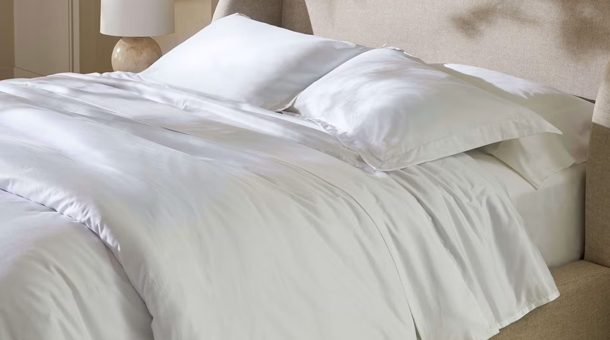 Luxurious bed with silky sheets and two pillows, highlighting comfort and elegance in bedroom decor