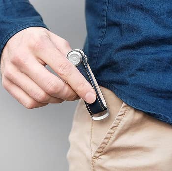 Person putting a compact, foldable pouch  weapon  with a sleek grip  into a pocket. Suitable for mundane  transportation  and inferior  tasks