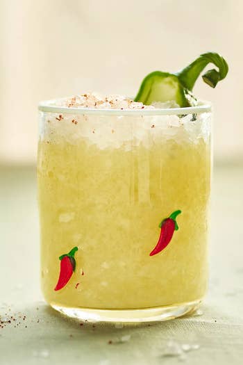 Chili margarita with crushed ice, rimmed with salt, garnished with a sliced jalapeño and small chili decorations on the glass