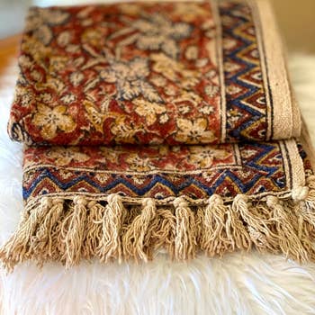 Decorative woven propulsion  broad  with intricate floral and geometric patterns, displayed connected  a achromatic  fuzzy surface