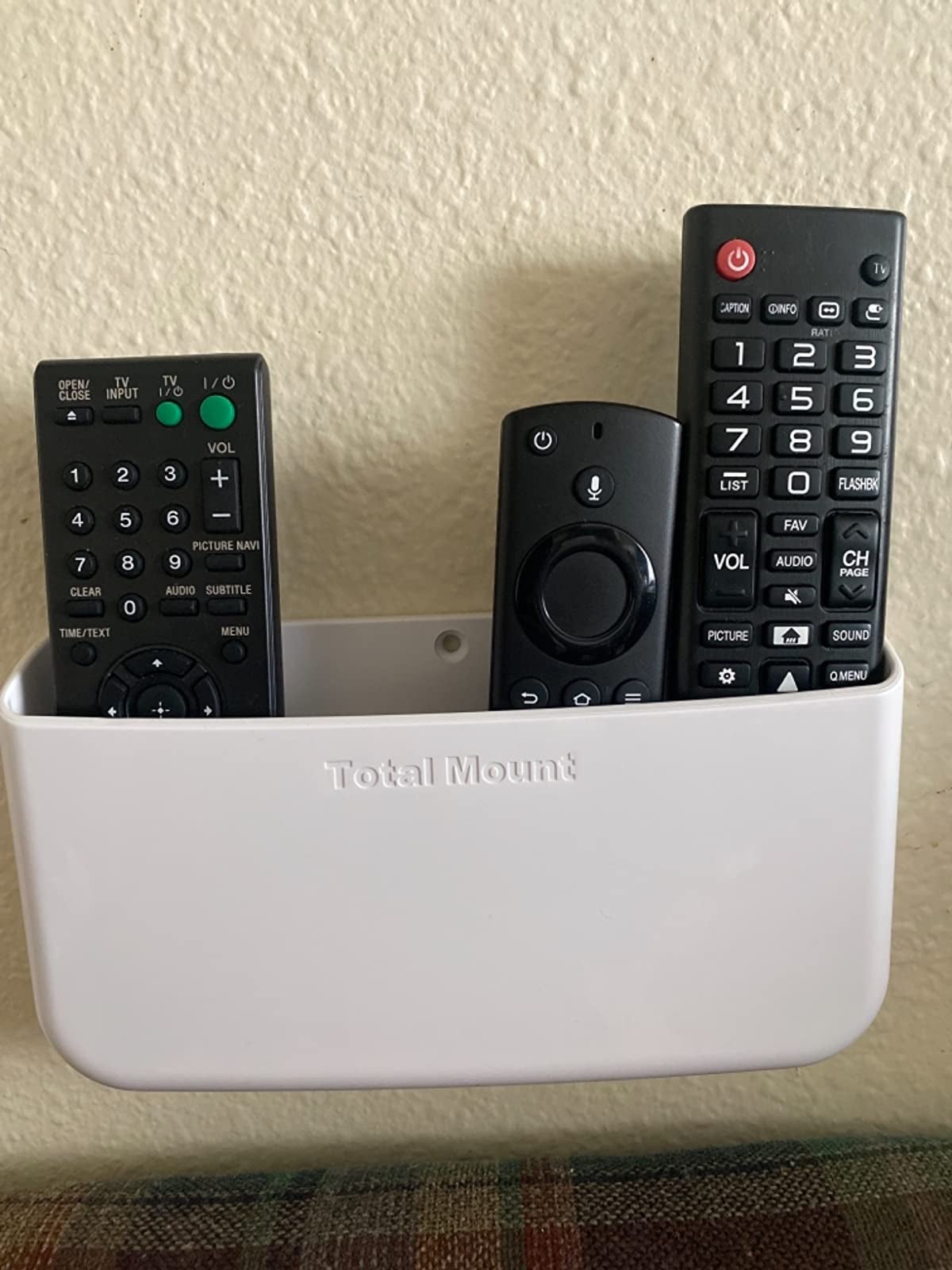 The remote holder mounted on the wall holding three remotes