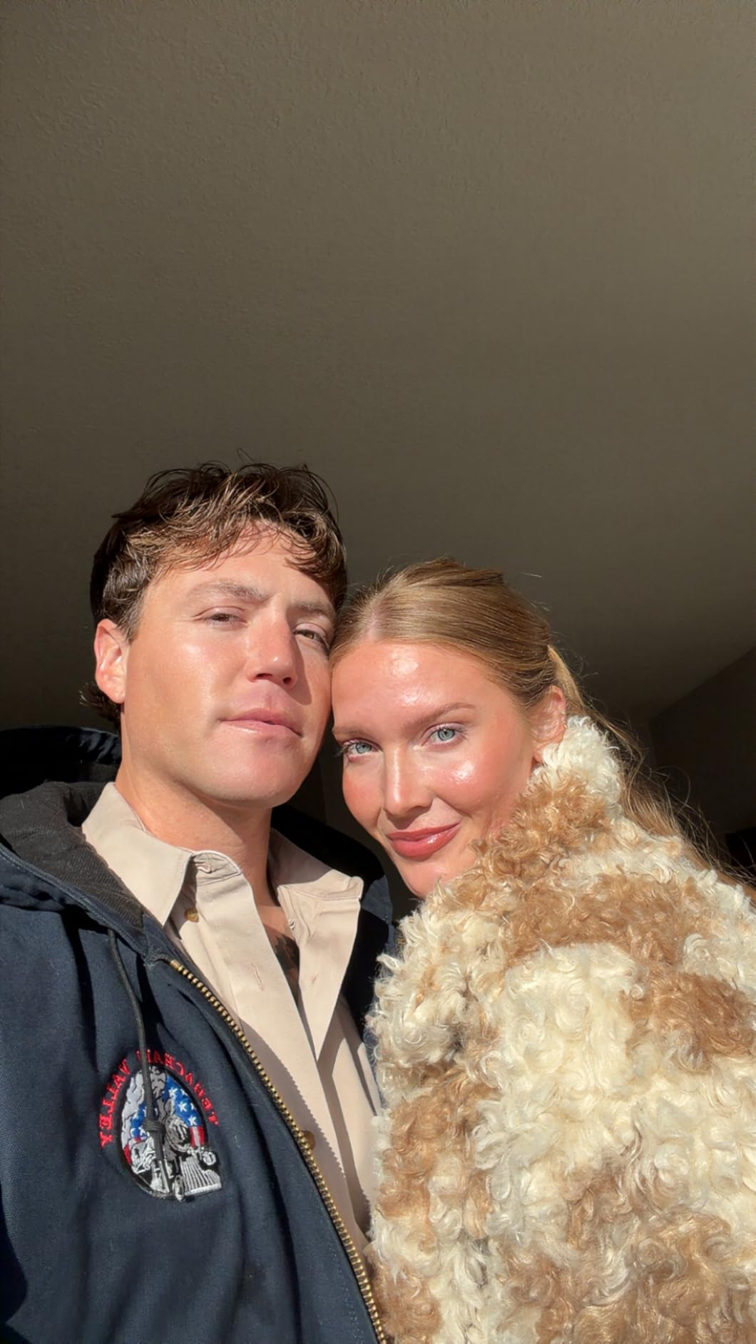 A antheral   successful  a casual overgarment   and a pistillate   successful  a stylish, fluffy overgarment  grin  for a selfie, suggesting a cozy, fashionable vibe