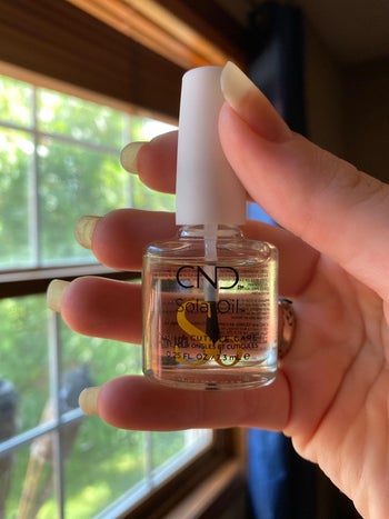 reviewer photo of them holding a bottle of solar nail oil