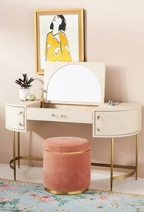 vanity with half-moon mirror, pink velvet stool, and round drawers
