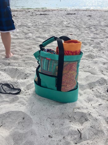 the tote on the beach filled with items