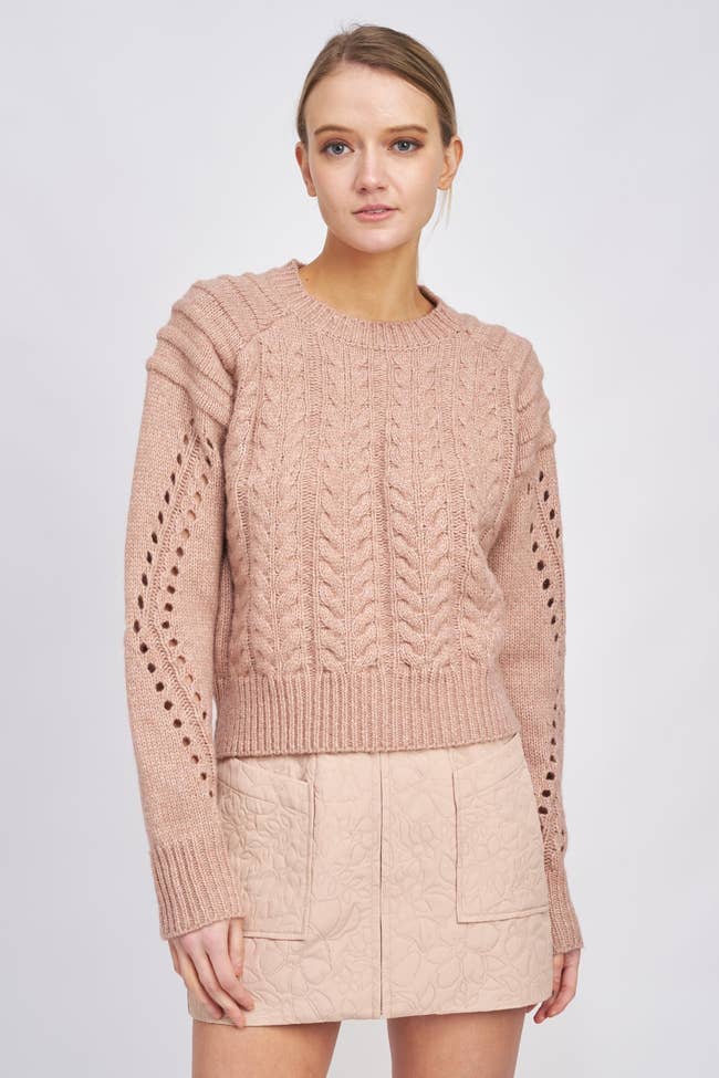 a model in a pink cableknit sweater