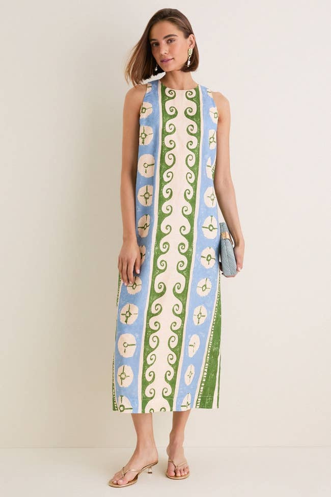 Model successful  a patterned sleeveless formal  and sandals holds a clutch, showcasing a stylish outfit suitable for shopping