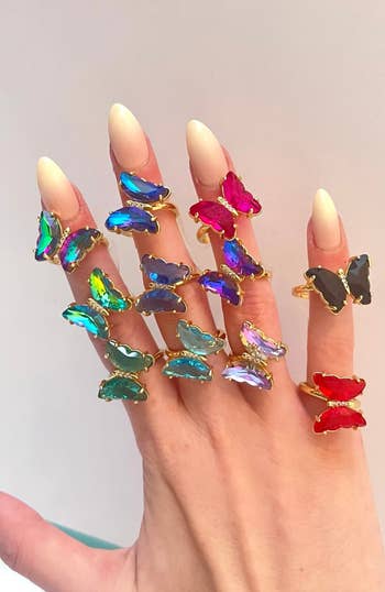 models hand with butterfly rings on it in different colors