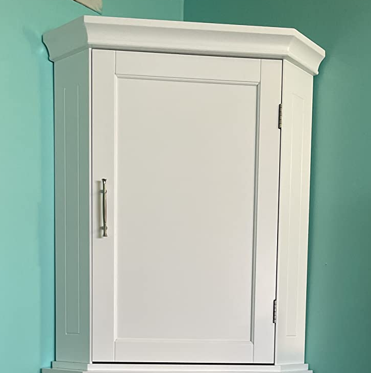 Reviewer image of small corner cabinet against a teal wall