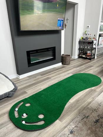 Indoor putting green mat with three golf balls in a room